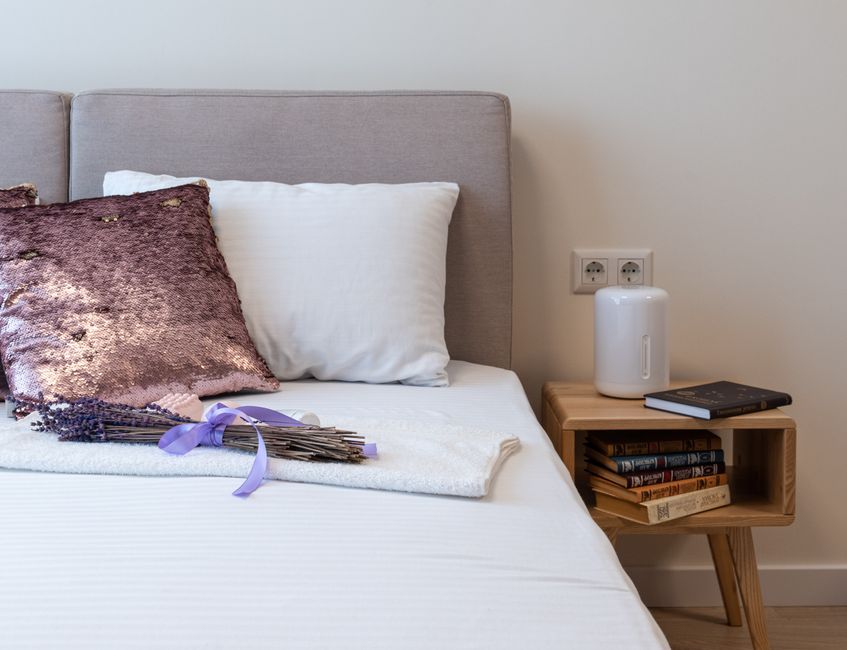 Aromatherapie met lavendelolie op nachtkastje.